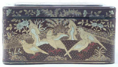 A Chinese export lacquer tea caddy in reddish earth colored lacquer having rounded corners decorated with two colors of gold depicting groups of birds highlighted in red lacquer. Circa 1840