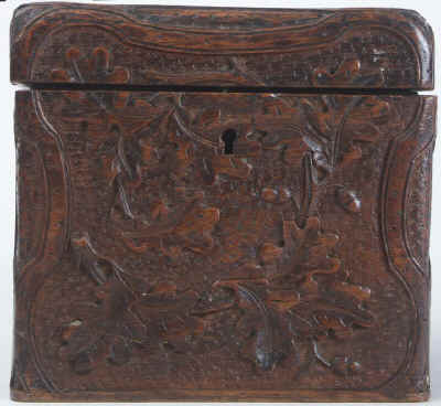 A tea caddy of cube form with the top and sides deeply carved depicting trailing oak leaves