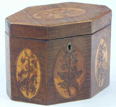 An Octagonal Caddy veneered in harewood and inlaid with oval marquetry panels depicting country flowers. Circa 1790