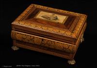 704JB: Ingeniously shaped box in rosewood and sycamore, decorated in penwork, inlay and a hand-colored print of idealised classical figures. It stands on the original gilded feet and has original handles. It is influenced by the second phase of the neoclassical tradition, when the early austere forms gave way to more monumental and even organic designs. An iconic gem of the period. inside it is lined with its original silk and has a replacement velvet covered tray. Circa 1815. 