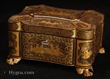 894TC: Chinese Export lacquer tea chest decorated with two colours of gold depicting scenes of Oriental life. The chest opens to two lift out pewter tea caddies or canisters. The caddy stands on gilded carved feet.  c1840