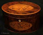 TC563: A well patinated oval burr yew caddy inlaid with a fine rendition of the Prince of Wales feathers above a crown. The design is sharply defined and subtly shaded by scorching the wood on a background of boxwood. The edgings and facings are boxwood. Circa 1790.