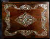 JB419: Mid Victorian box veneered in dark rosewood and decorated with mother of pearl. The pattern of the decoration is controlled and symmetrical but it also swirls in the more naturalistic style of the later 19th century. The motifs are of stylised flora which is accented with centres of darker abalone shell. The box has a spring-out side drawer covered in original silk. The interior has been fitted with another tray. The back lid retains its original drop down envelope compartment covered in original ruched velvet.  Small repairs and minute losses to mother of pearl visible under close scrutiny. The box has a working lock and key. Circa 1870. Enlarge Picture