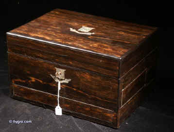 JB319: A fully fitted and intricate dressing box  by C. Henry of Manchester in figured coromandel inlaid with engraved shield to the top and escutcheon  in mother of pearl opening to a compartmentalized interior and retaining its original chased silver toped cut  lead crystal jars and bottles by Thomas Whitehouse and having two sprung drawers fitted for jewelry. There is a liftout mirror with gold embossed mirror in the lid and a blind embossed leather document wallet behind. Circa 1860. Enlarge Picture