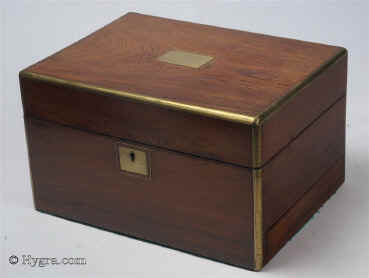 JB445: Figured Rosewood box edged in rounded brass circa 1850.  A three layered box with a lift out tray and a sprung side drawer. The tray has been fitted with velvet covers in order to protect the original surface whilst making the interior easier to use. The fold-down envelope on the lid retains its original ruched velvet and gold embossed leather framing. The rounded brass accents and protects the box and gives the corners a nice finish. Crack on veneer on top. Working lock and key. Enlarge Picture