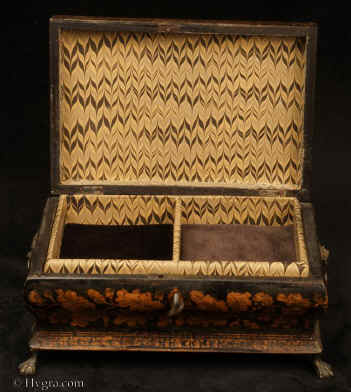 JB553:Shaped penwork box of complex casket form, the sides decorated with depictions of flora the top has a depiction of figures in front of a cottage with ruins in the background. The box has been relined and has a liftout tray. The box stands on clawed feet and has embossed gilded brass drop handles. Circa 1830. Enlarge Picture