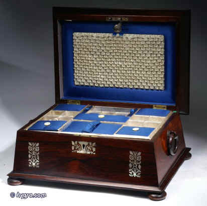 SB125: Antique  figured rosewood sewing box the top panel framed  inlaid with mother of pearl to the top and front having turned rosewood drop-ring handles and standing on  turned bun  feet. Inside the lid is lined with contrasting blue and cream silk and has a document wallet behind. The box has a liftout tray with supplementary lids covered in silk. Circa 1830. Enlarge Picture