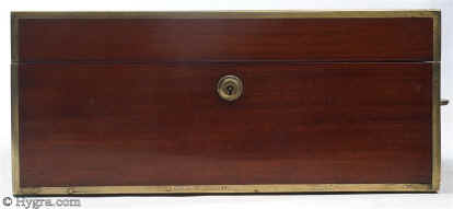 SB454: Mahogany and brass bound sewing box circa 1820. This is a most unusual early sewing box, both strong and robust. The high quality of the structure suggests that it was made to withstand travel as well as sit in elegant drawing rooms. The mahogany is edged in squared brass all around and bears flat-folding side handles. The original interior is lined in red textured leather. The tray is in keeping with the exterior and is structured for strength. The envelope is most unusual and opens with a silver catch. Some bending on bottom brass suggesting that the box did travel! Working Bramah lock and key.  Enlarge Picture