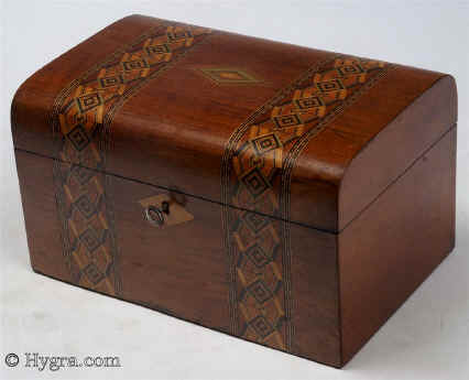SB457: Walnut veneered box  inlaid  with bandings of parquetry circa 1880. A box of pleasing structure with a rounded top and original interior. The inlay is within the genre of mid to late 19th century, but it has greater complexity than the average example of such work. Working lock and key.
               Enlarge Picture