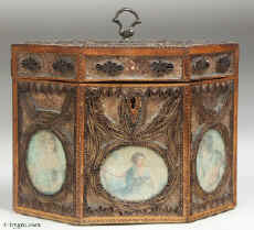 A late 18th century rolled paper  tea caddy the framed panels of  filigree spaced ornament on a background of mica flakes and having colored prints of classical inspiration under glass. The caddy is framed with fruitwood inlaid with a chevron of dark and light wood. Enlarge Picture