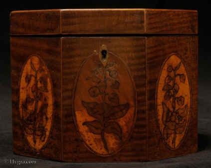 TC131: An Octagonal Caddy veneered in harewood having boxwood stringing and inlaid with
            oval marquetry panels depicting country flowers. Circa 1790.Enlarge Picture