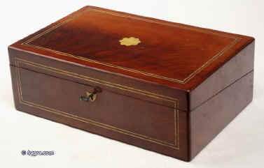 WB166: Figured mahogany writing box inlaid with brass accents and rounded edges opening to a writing tablet still retaining is Tyrian purple velvet surface and having compartments for writing tools and further compartments under the sloping writing surface for storing paper. Circa 1825. Enlarge Picture