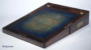 WB168 Antique figured rosewood writing box with rounded edges, and countersunk brass carrying handles, name plate and escutcheon , inlaid to the top and front with  inlays of white metal, opening to an embossed leather writing surface and compartments for writing implements and paper. The box also has secret drawers hidden behind a sliding panel. Circa 1840.  Enlarge Picture