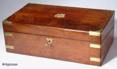 WB171: Flame mahogany writing box with brass shield shape name plate, and escutcheon, brass corners and straps opening to a fitted interior with velvet covered writing slope, compartments for writing tools and inkwells. Under the writing surface there are places for storing papers. There are also secret drawers concealed behind a sprung panel released by pulling on one of the divisions. Circa 1845. Enlarge Picture