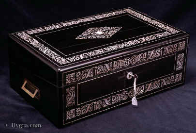 WB468: Writing box veneered in saw cut ebony veneer inlaid with mother of pearl circa 1840. This box is of outstanding quality. The beautifully iridescent mother of pearl enlivens the austere ebony which in turn provides a complimentary background with its subtle dark sheen. The design is of stylised flora which refers to the neoclassical tradition of the late 18th and early 19th century, but looks forward to the later period with its undulations and loops which suggest real plant growth. The pattern with its swirling symmetry suggests the moment in aesthetic history when the poise of neoclassicism was injected with the energy of naturalism, without losing control of design or tightness of execution. The flowers and leaves are exquisite. There are small sunflowers and acanthus leaves and a stylised split acanthus with a diamond shape in the centre of the ebony. The acanthus is a classical motif, but here it takes its place in a rich and vibrant design intermingling with trellised and swirling plant life. The central design forms a diamond made up of four triangles centred by a circle. The triangles are a tour de force of symmetry, a true technical feat. The rounded floral motifs are contained within the straight lines of the overall design. The stems are incredibly thin as are many of the other elements which form the flowers and leaves. Bearing in mind that ebony and shell are very hard materials, such work requires skill of the highest calibre and a considerable amount of time. The lines which form the design are very delicate and yet they build up to a pattern of strength and vitality.   Enlarge Picture