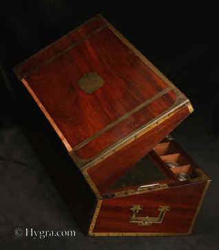 WB475: Important rare brass bound  solid mahogany ship captain's campaign writing box with complex secret drawers and compartments including a false bottom.  The box retains its original green felt writing surface, pounce  and inkwell. The box also has a screw down mechanism enabling it  be attached to a table. There is also a reading stand which is attached to the top surface when the box is held at an angle with an adjustable hinged brass catch. Circa 1800. Enlarge Picture