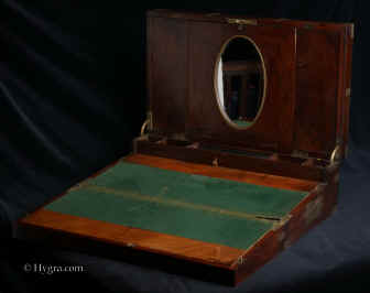 WB479: Early 19th Century brass bound solid flame mahogany triple opening  writing box with unusual features such as visible dovetail construction. It opens up to a green baize writing surface a high back with central oval  framed mirror, spaces for storing papers, compartments for pens, inkwell and pounce pot, and other writing accessories. There is a nest of secret drawers under the pen tray.Circa 1830. Enlarge Picture
