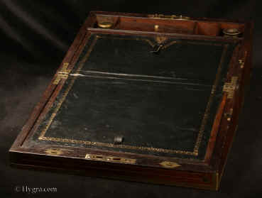  WB483: Regency brass edged  figured rosewood  writing box with brass accents, countersunk brass handles opening to an embossed leather writing surface (replacement) and compartments for pens and inkwells, having compartments for paper under the flaps. There  are secret drawers under the pen compartment concealed behind a sprung flap released by pulling up the wall  of the right inkwell compartment.  The box has two locks. The main one is Bramah and slightly later than the box.  one of the flaps also has a  lock. There is a side drawer for more papers. Circa 1820 Enlarge  picture