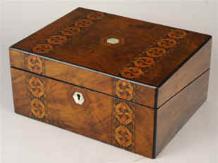 Victoria writing box veneered in figured walnut and inlaid in strips of geometric marquetry of light and stained woods opening to a green velvet writing surface and compartments for pens and writing implements.  Circa 1880. Enlarge Picture