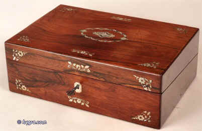A figured rosewood writing box inlaid with floral motifs depicted in contrasting mother of pearl and abalone, opening to a Tyrian purple velvet writing slope and compartments  for writing tools and further compartments for stationary under the flaps. circa 1840 Enlarge Picture