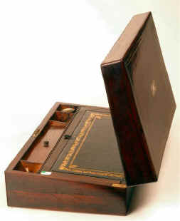  Antique writing box with rounded edges, mother of pearl and white-metal inlay opening to compartments for writing instruments, retaining an original faceted inkwell, having further compartments for paper, under the writing surfaces which have been recovered with  gold embossed leather. circa 1840 Enlarge Picture