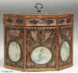 A late 18th century rolled paper  tea caddy the framed panels of  filigree spaced ornament on a background of mica flakes and having colored prints of classical inspiration under glass. The caddy is framed with fruitwood inlaid with a chevron of dark and light wood. Enlarge Picture