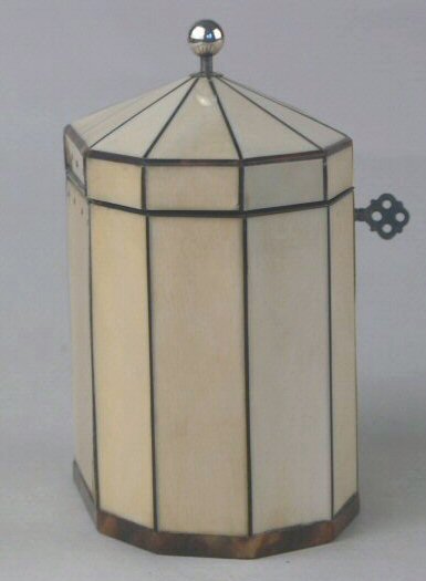 Hygra: A ten sided tortoiseshell strung ivory  tea caddy with a pyramid top  having a silver ball finial,   a silver escutcheon, and silver plaque on the front encircled with pique point. Circa 1790.