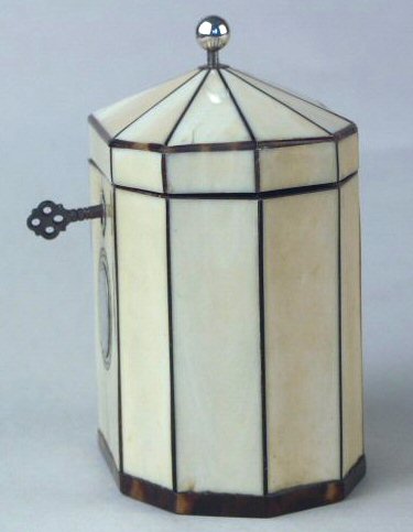 Hygra: A ten sided tortoiseshell strung ivory  tea caddy with a pyramid top  having a silver ball finial,   a silver escutcheon, and silver plaque on the front encircled with pique point. Circa 1790.