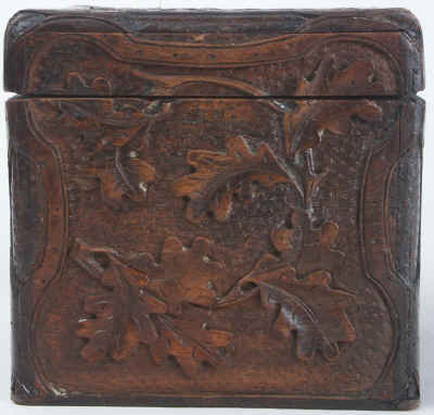 A tea caddy of cube form with the top and sides deeply carved depicting trailing oak leaves