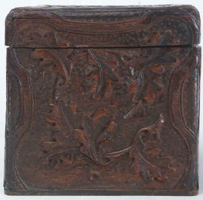 A tea caddy of cube form with the top and sides deeply carved depicting trailing oak leaves