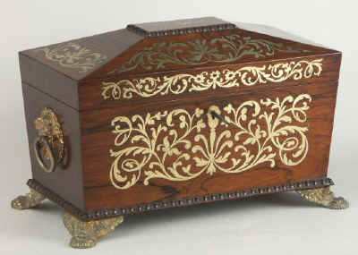 A Rosewood three compartment  brass Inlaid Tea Chest with gadrooned framings having twin lift-out  wooden canisters flanking a cut crystal bowl standing on embossed gilded brass feet and with drop handles, Circa 1825.