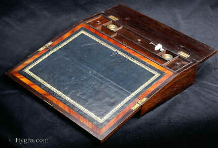 WB463: Writing slope in rosewood with brass inlay circa 1820. It is veneered in saw cut rosewood on mahogany and it is inlaid in brass.Inside the box has lidded compartments for pens, wax etc and two screw top distinctive inkwells. Enlarge Picture